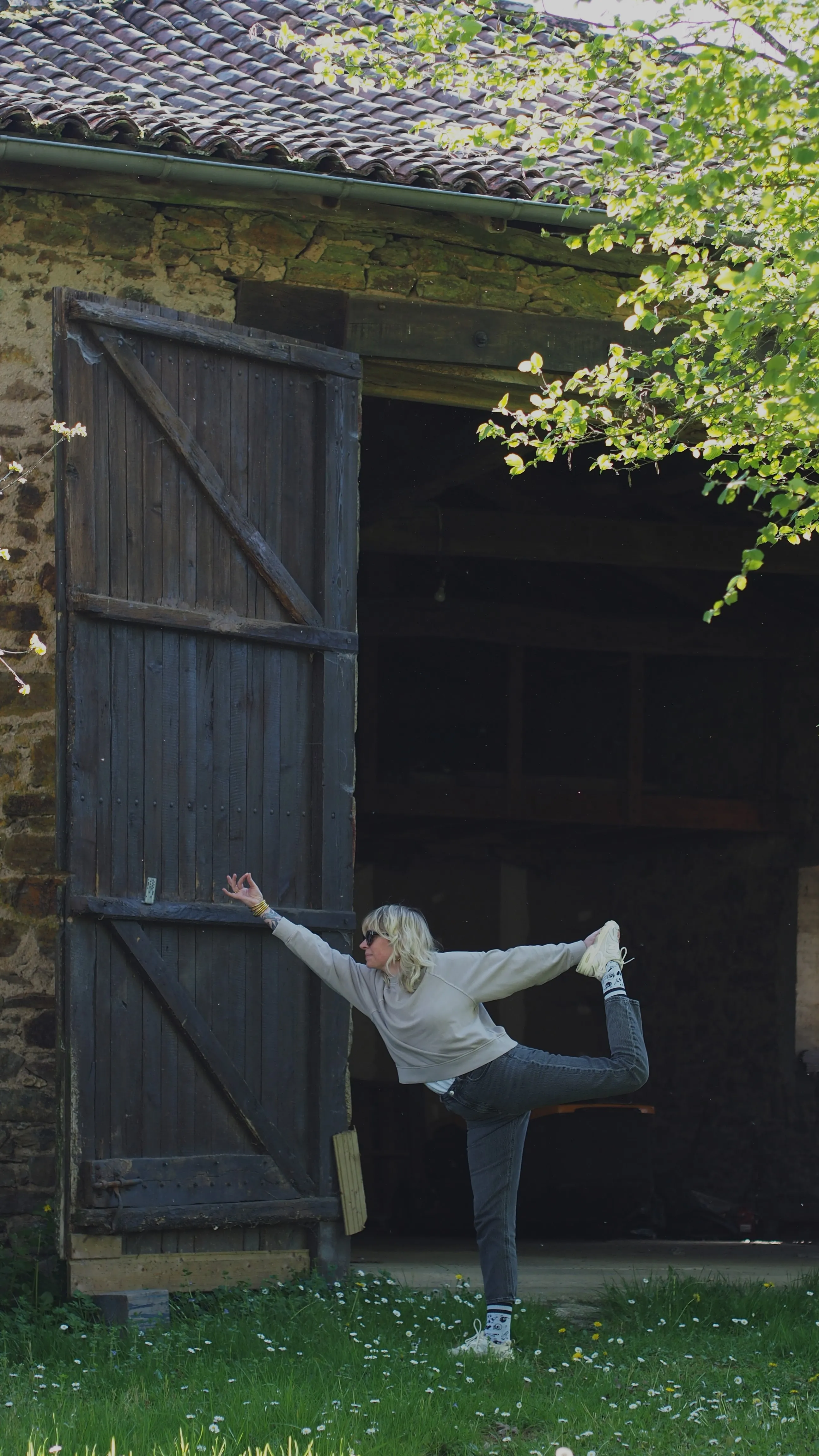 Edwige en posture du danseur devant la porte en bois de la grange