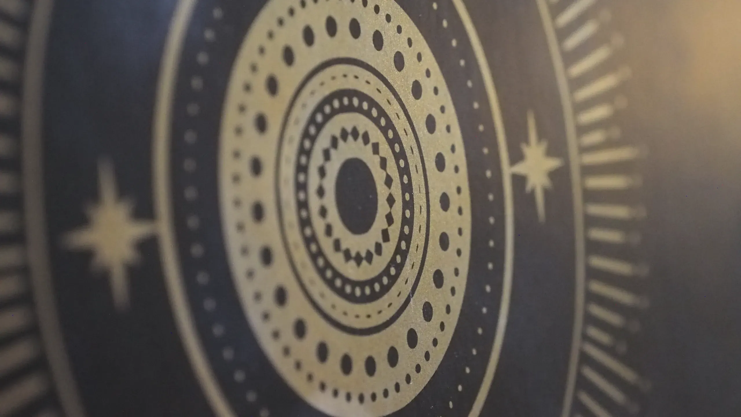 Détail d’un tapis de yoga, rosace dorée et étoiles sur fond sombre