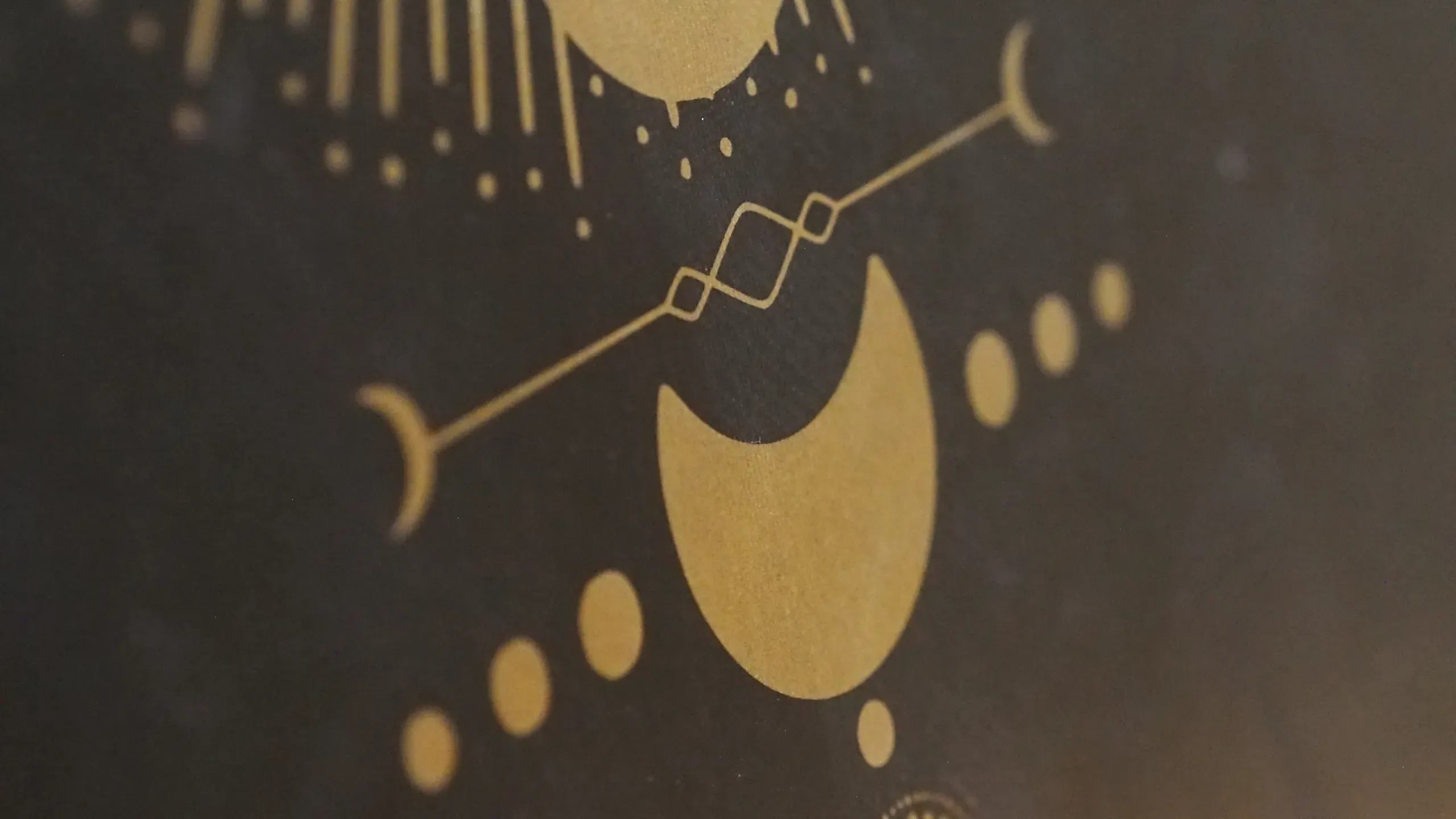 Détail d’un tapis de yoga, motif céleste doré sur fond sombre