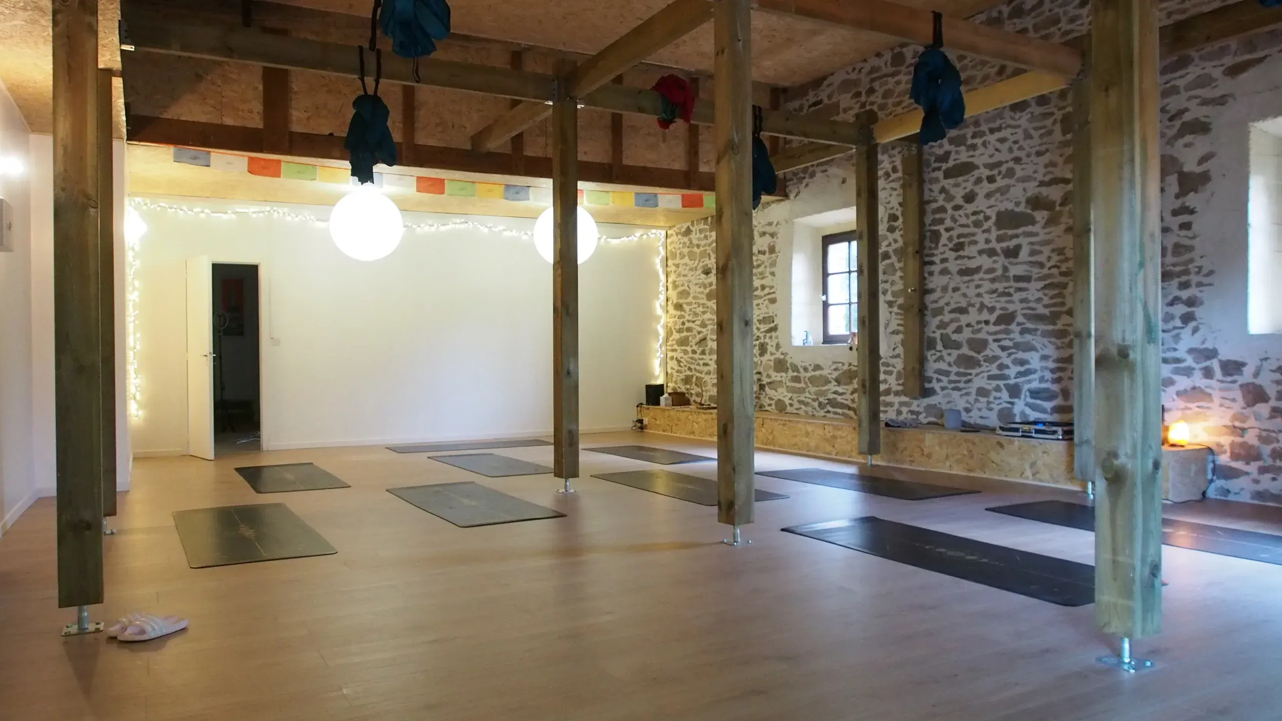 La salle de cours collectifs, hamacs et tapis dans la grange en pierres