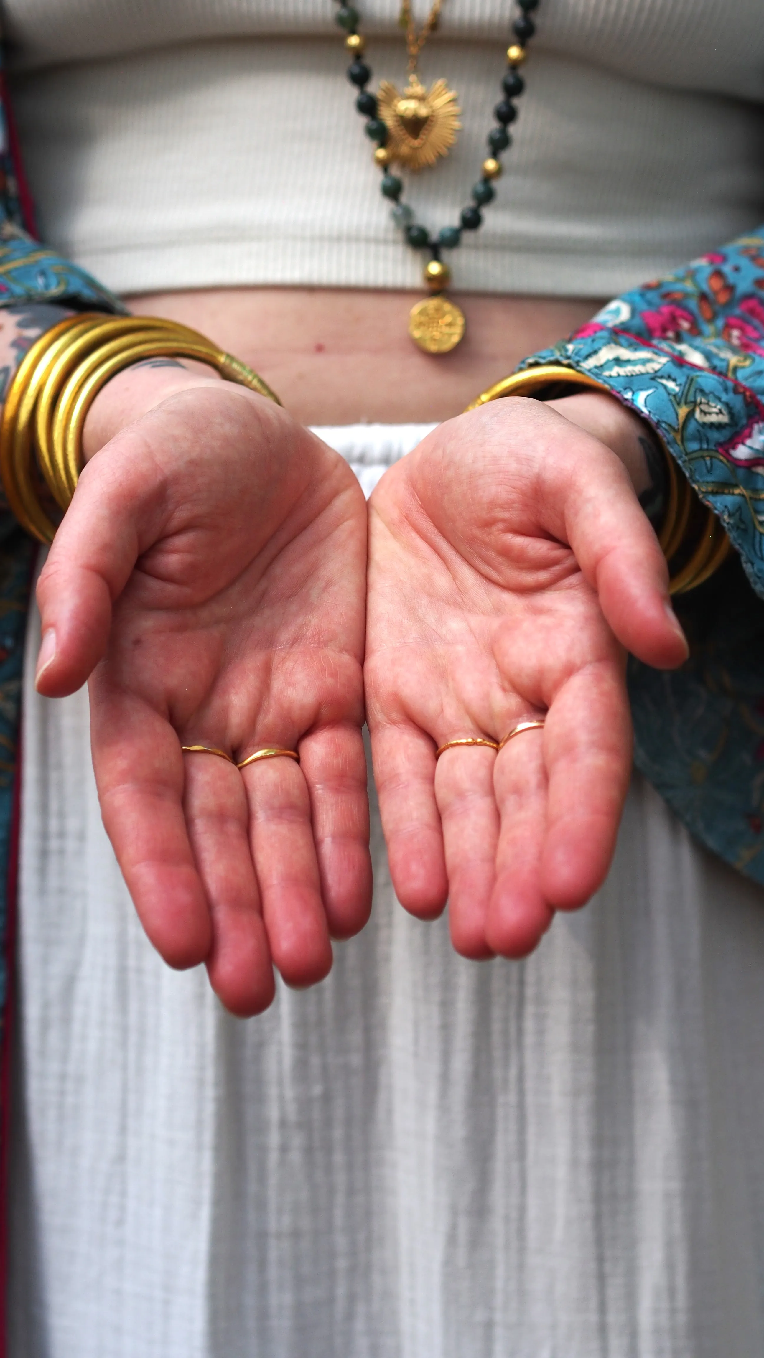 Deux mains ouvertes, paumes vers le ciel, bracelets dorés aux poignets