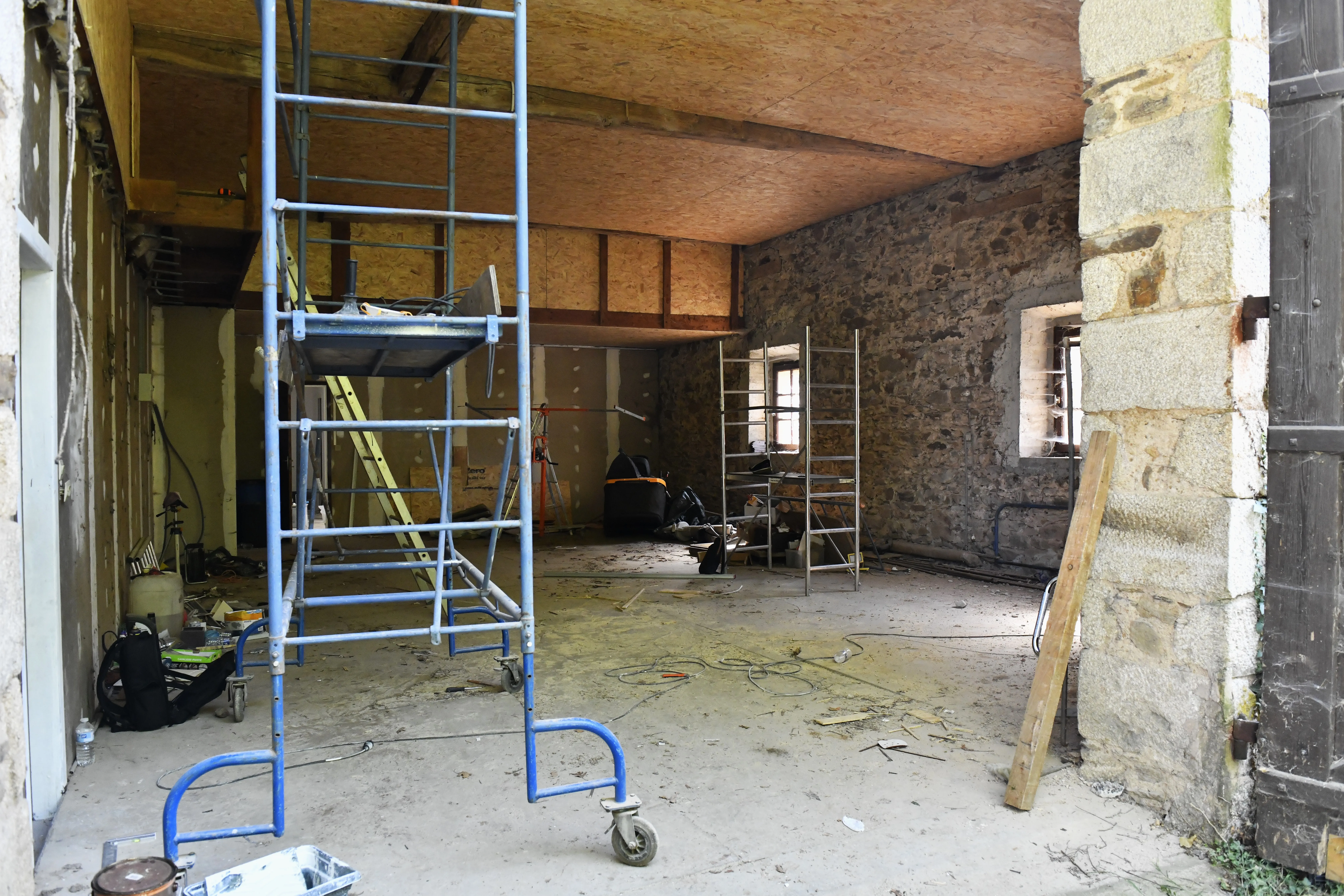 L’intérieur de la grange en plein chantier, échafaudage au milieu des murs en pierres