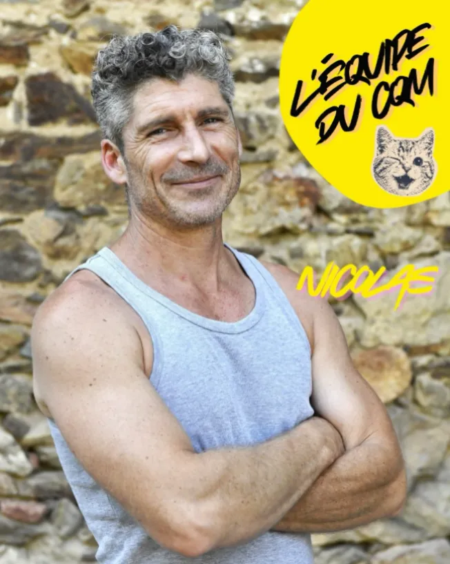 Nicolas Fichot souriant, bras croisés devant le mur en pierres, l’équipe du Chat Qui Médite